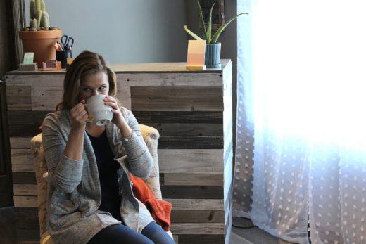 Eva enjoys a cup of coffee in a chair in front of a window